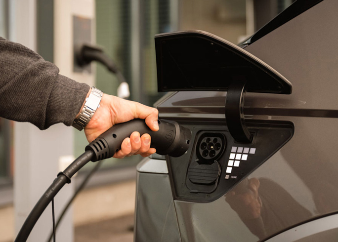 Hand plugging in charger to electric car