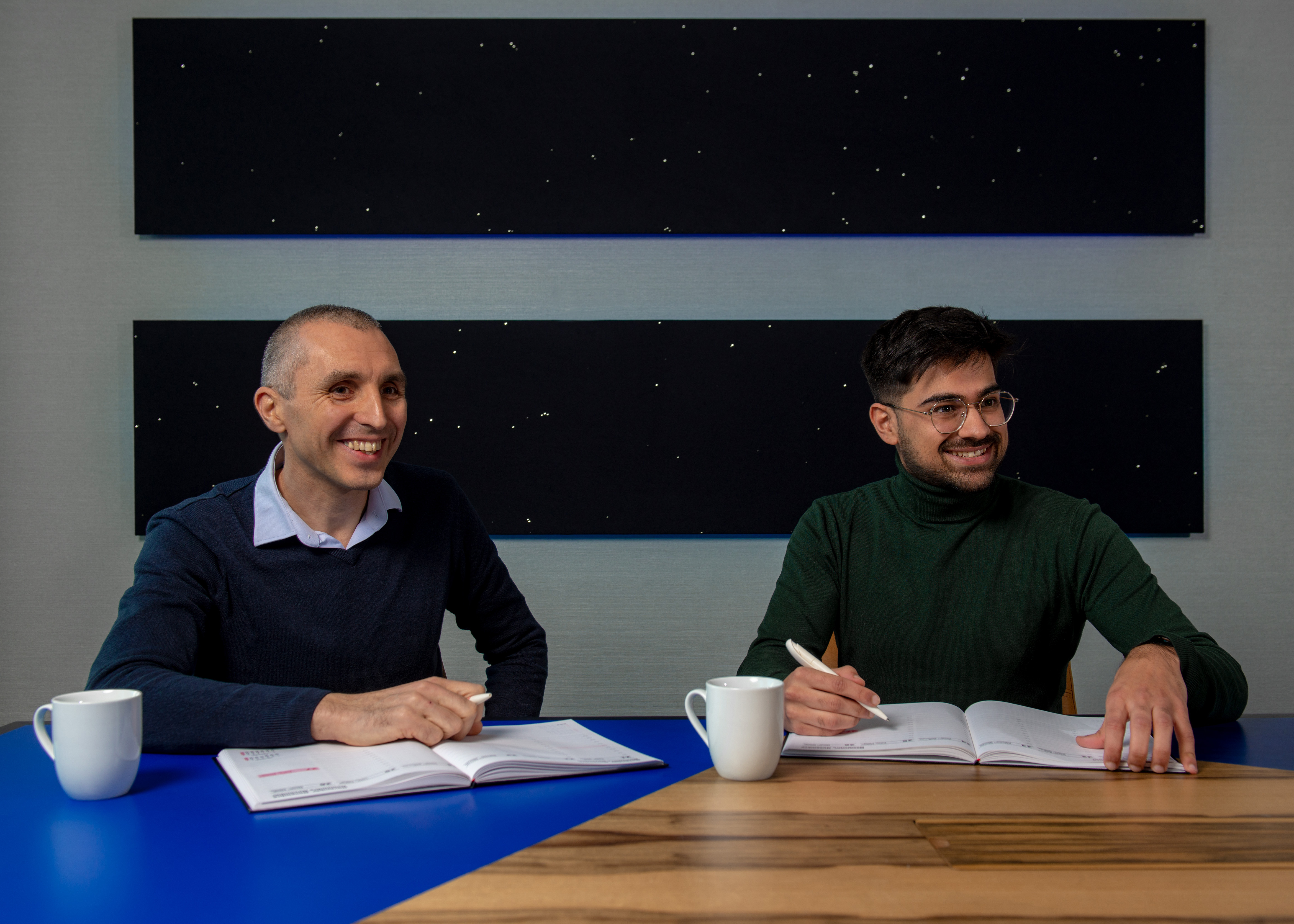 Two people with notebooks in a meeting