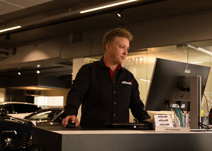 Autohalle sale person at desk on computer 