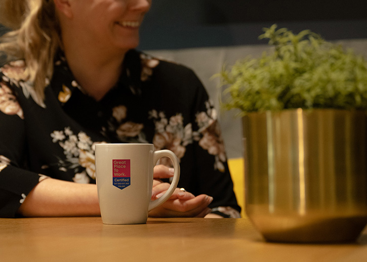 Person at table with a Great Place To Work mug