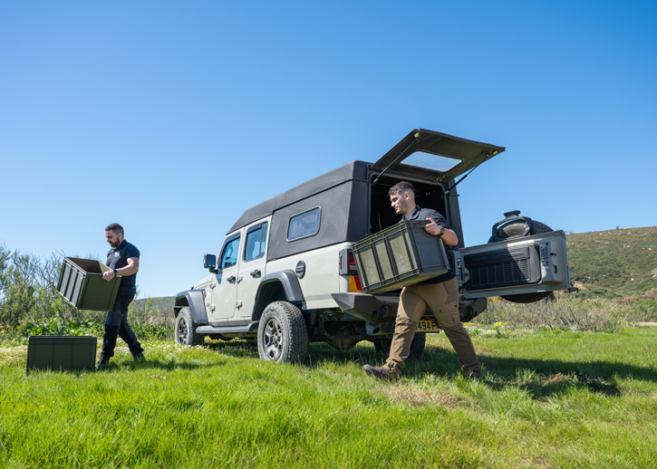 People unloading boxes from AADS Jeep in a field