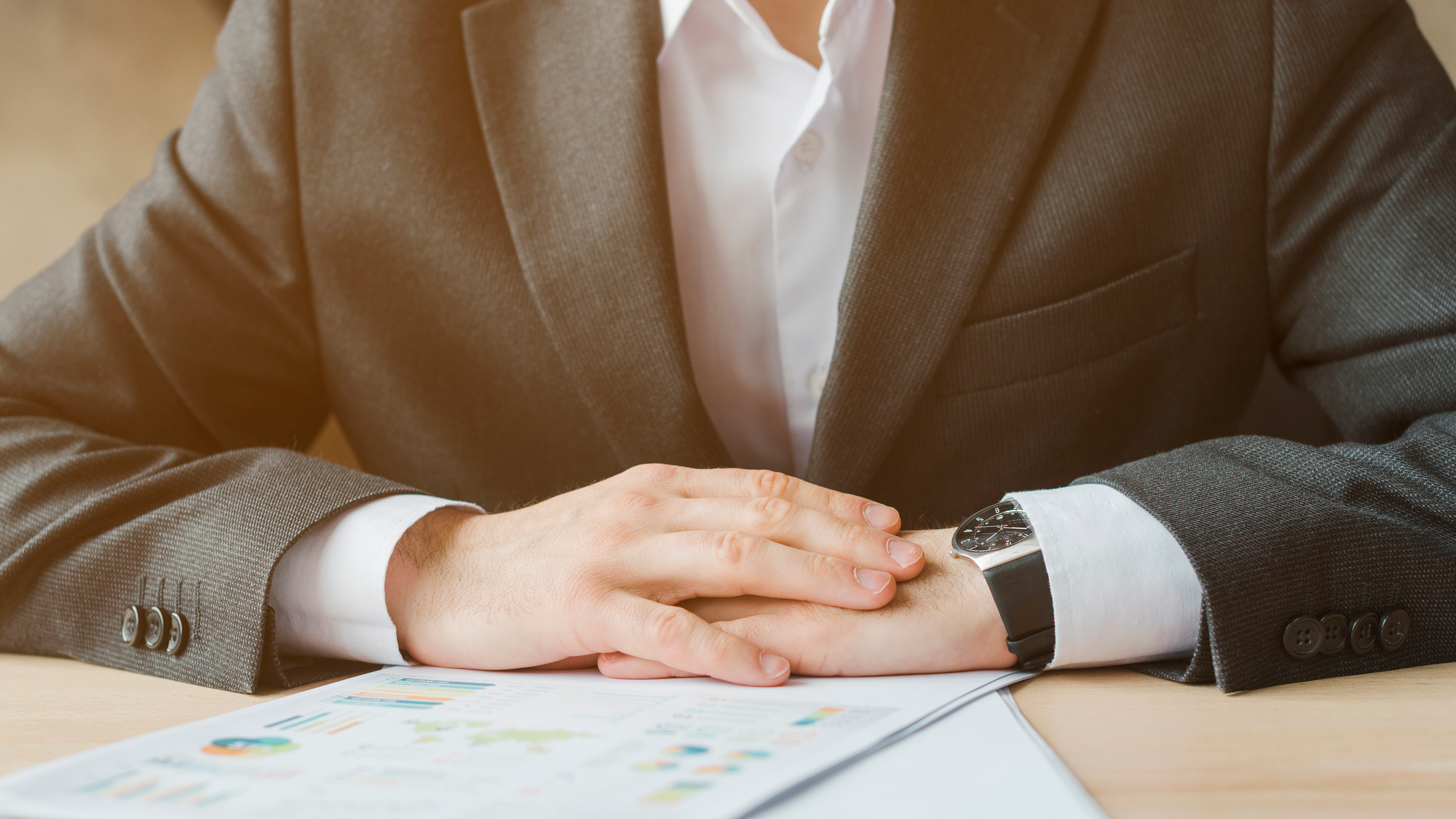 Close up of suited person with hands on desk
