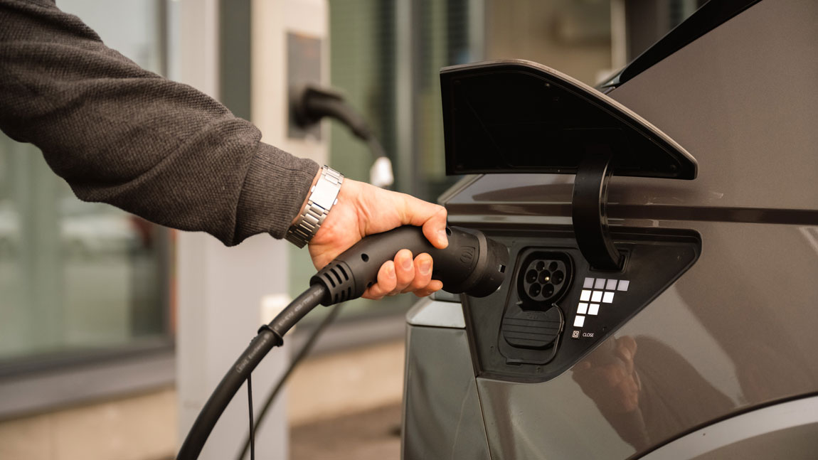 Hand plugging in charger to electric car