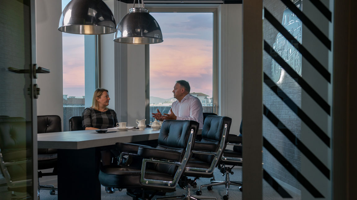 Two people having a conversation over tea in a conference room