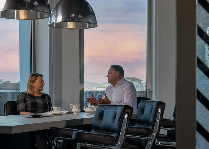 Two people having a conversation over tea in a conference room